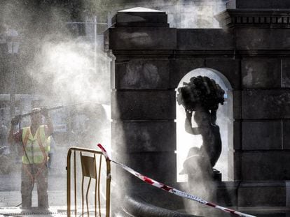 Operario limpiando una escultura en la plaza Catalunya de Barcelona.