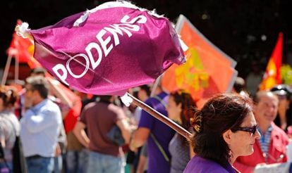 Una asistente con una bandera de Podemos, en un mitín de Unidos Podemos en Ciudad Real. Al fondo, una bandera comunista.