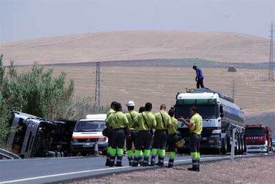 Un grupo de bomberos espera cerca del camión siniestrado ayer en Córdoba para proceder al trasvase de la mercancía vertida durante el siniestro.