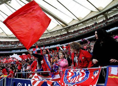 Aficionadas del Atlético exhiben banderas rojiblancas en las gradas.