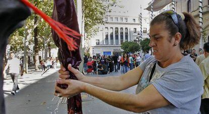 Una ocupante de los pisos de La Utopía lava ropa frente al Ayuntamiento de Sevilla como protesta.