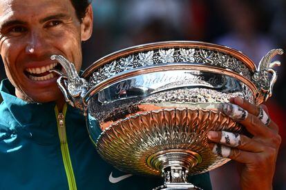  Ocurra lo que ocurra, en París se alinean los astros. Rafa Nadal, 36 años y mil batallas a las espaldas, cuerpo magullado y una lesión en el pie que arrastra desde su debut profesional, ha resuelto la final de Roland Garros contra el noruego Casper Ruud sin vacilaciones (6-3, 6-3 y 6-0, en 2 horas y 18 minutos) y ha elevado al cielo parisino su 22º Grand Slam, dos ya por delante del suizo Roger Federer y el serbio Novak Djokovic. En la imagen, el tenista, dominador absoluto en tierra batida, muerde su decimocuarta Copa de Mosqueteros. 
