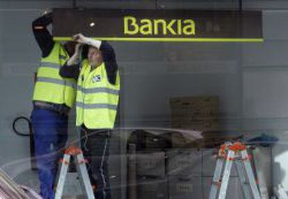 Dos trabajadores colocan el logotipo de Bankia