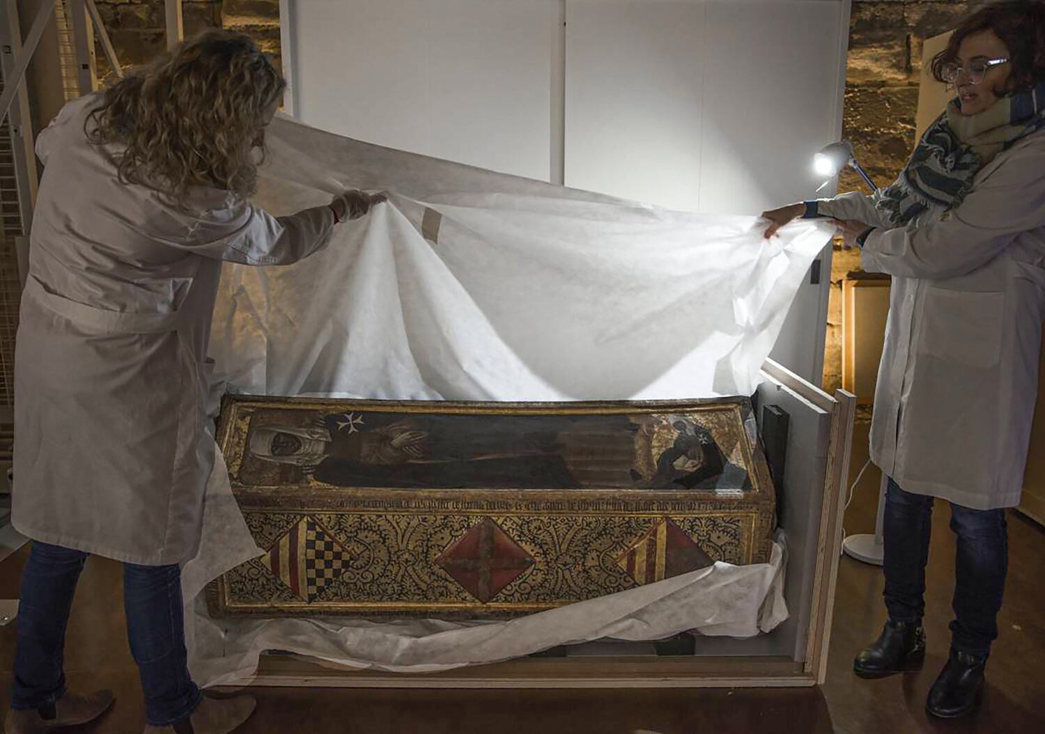 Dos conservadoras desembalan la caja mortuoria de Isabel de Aragón en el monasterio de Sijena tras su llegada desde el Museo de Lleida.