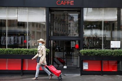 Una mujer camina delante de un restaurante cerrado en París, capital de Francia.