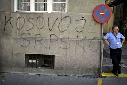 Un hombre espera junto a una pintada en Belgrado que reza "Kosovo es Serbia"