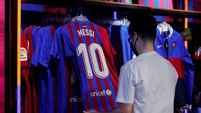 Un aficionado mira una camiseta de Messi en una tienda de Barcelona.