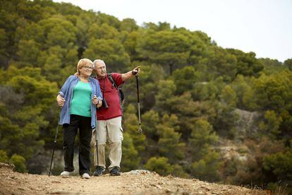 Una pareja de senderistas 'seniors' caminando por un bosque mediterráneo en España.