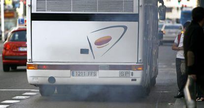 Un autocar expulsa gases por el tubo de escape circulando por el carril bus de la Gran Vía madrileña.