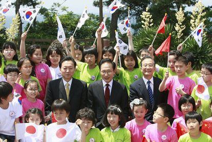El presidente surcoreano, Lee Myung-bak, flanqueado por el primer ministro japonés, Yukio Hatoyama (izquierda), y el jefe del Gobierno chino, Wen Jiabao, rodeados de niños, ayer en la isla surcoreana de Jeju.