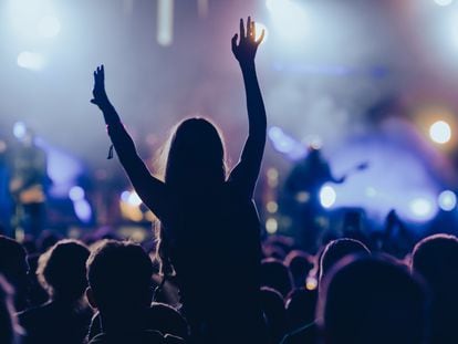 Una joven en una multitud durante un concierto en un festival de música al aire libre.