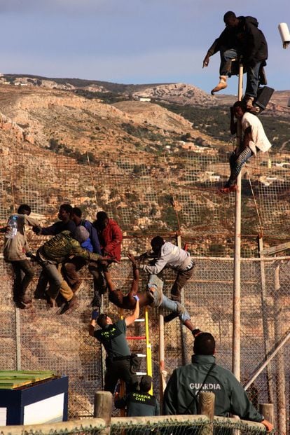 Inmigrantes subsaharianos quedan atrapados en lo alto de la valla fronteriza de Melilla tras un intento de salto en enero de 2000 mientras la Guardia Civil intenta bajarlos.