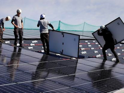 Varios operarios instalan paneles solares en el tejado de una planta industrial en Vic (Barcelona).