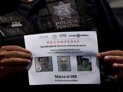 Un policía muestra el letrero de "Se Busca" de El Chapo.