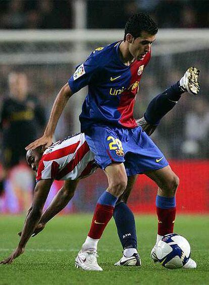 Busquets controla un balón ante la oposición de Sinama-Pongolle, en el partido Barcelona-Atlético de Madrid.