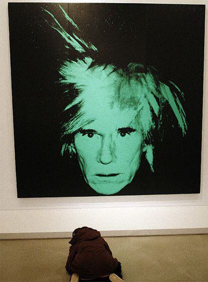 Un estudiante escribe notas ante un autorretrato de Andy Warhol.