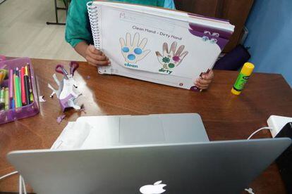 Un niño muestra un trabajo a su maestra a través de una videollamada.