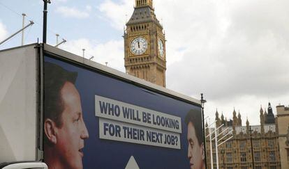 Una furgoneta con un cartel en el que aparecen el primer ministro británico, David Cameron, y el líder de la oposición laborista, Ed Miliband, y la pregunta quién estará buscando un próximo trabajo recorre los alrededores de la plaza del Parlamento en Londres.
