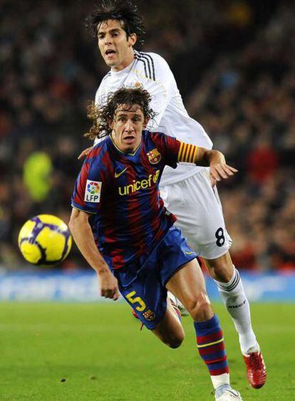 Puyol presigue el balón junto a Kaká.