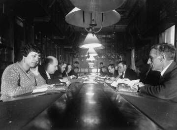 Diverses persones en una taula de la biblioteca de l'Ateneu Barcelonès. A l'esquerra, en primer terme, Llucieta Canyà; el segon, Josep Maria de Sagarra. A la dreta, en primer terme, Pompeu Fabra.
