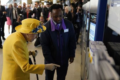 Isabel II, utilizando una de las máquinas expendedoras de billetes de metro, en la estación de Paddington, en Londres, este martes.