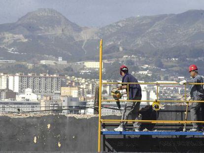 Unos obreros, en el andamio de una obra, en Ceuta.