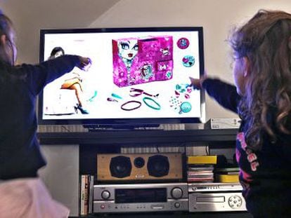 Dos niñas miran un anuncio en televisión.