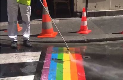 Un operario limpia las pintadas sobre la bandera LGTBI en una calle de París.