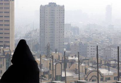 Una mujer observa la neblina y el humo entre los edificios en Teher&aacute;n (Ir&aacute;n) 