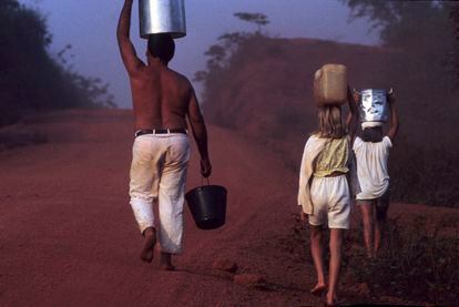En noviembre de 2017, un padre camina con sus hijas cargando cubetas de agua por la carretera Transamazónica, en el Estado de Pará (Brasil).