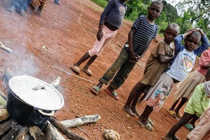 Los niños esperan impacientes a que se cocine la papilla.