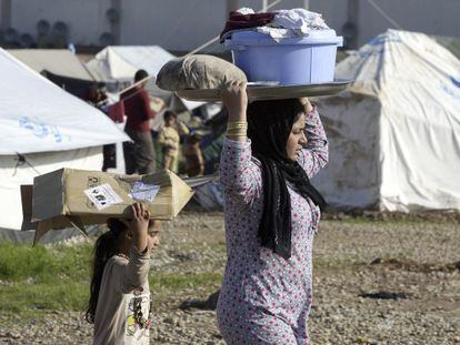 Una mujer yazidí y una niña llevan en el campo de refugiados de Baharka, en Irak