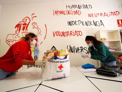Una voluntaria de Cruz Roja entrega una bolsa con productos de primera necesidad a una joven en Valencia.