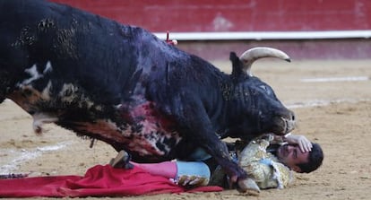 El torero Enrique Ponce se protege la cara al caer al suelo cogido por su primer toro en la corrida de este martes en Valencia.