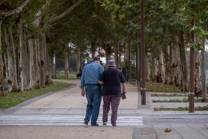 Una pareja de ancianos camina por la calle agarrada del brazo.