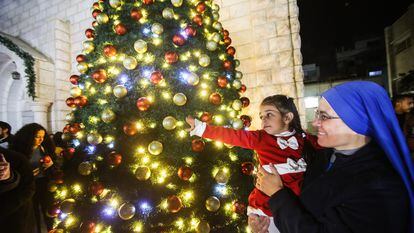 Una religiosa acerca a una niña palestina al árbol de Navidad de la iglesia de la Sagrada Familia, el día 18 en Gaza.