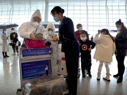 Una familia en traje protector intenta embarcar en el aeropuerto de Wuhan
