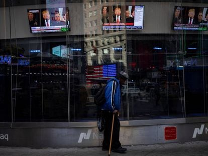Un hombre pasa por delante de un escaparate con imágenes de un discurso del presidente de EE UU, Donald Trump, en Nueva York. 