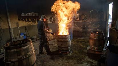 Un operario quema el interior de uno de los toneles elaborados para la fabricación de whisky en la empresa Tonelería del Sur, en Montilla, Córdoba.