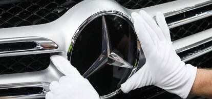 Foto de archivo de un trabajador mientras coloca la estrella de Mercedes Benz en la parrilla frontal de un vehículo.