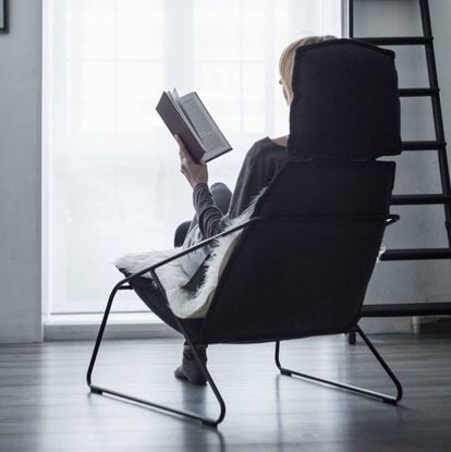 Persona leyendo sentada en un sillón.