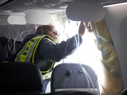 Un inspector de la Junta Nacional de Seguridad en el Transporte examina el hueco en el fuselaje del avión de Alaska Airlines que tuvo que hacer un aterrizaje de emergencia en Portland (Oregón) el viernes.