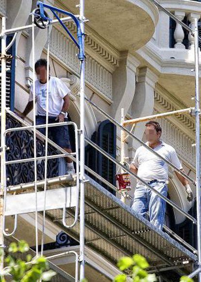 Dos obreros trabajan en una fachada subidos en un andamio y sin arnés de seguridad ni casco