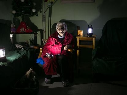 En la imagen, Rosa (73 anos) iluminada con linternas en el salón de su casa durante un corte de luz.
