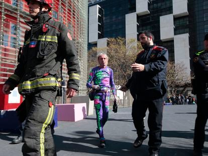 French urban climber, Alain Robert, is escorted by police after scaling the 144 meters (472 ft) of the Glories tower with the La Sagrada Familia Basilica designed by architect Antoni Gaudi in the background, left, in Barcelona, Spain, Wednesday, March 4, 2020. Robert, known as Spiderman climbed up 144 meters of the Glories tower, previously known the Agbar tower in around 20 minutes. Spanish authorities briefly detained him after the stunt. (AP Photo/Joan Mateu)