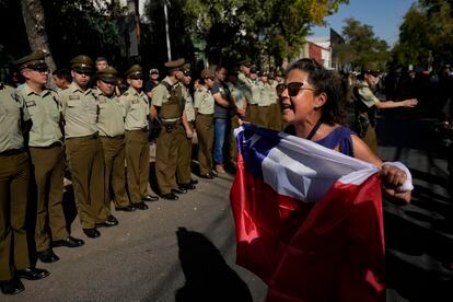 Una mujer sostenía el jueves una bandera de Chile durante una procesión fúnebre por un policía asesinado en Santiago.