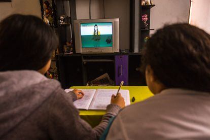 Dos niñas peruanas estudiando frente a la televisión durante la pandemia.