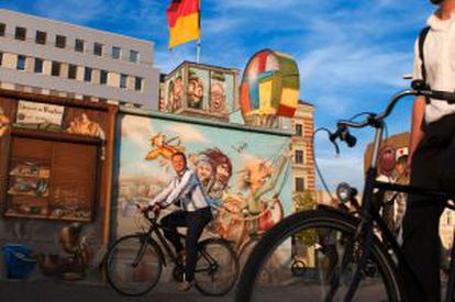 Ciclistas paseando por la East Side Gallery de Berlín al atardecer.