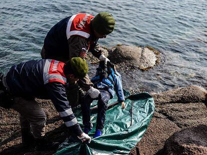 Policías turcos colocan el cuerpo de un niño ahogado en una bolsa en la costa de Çanakkale.