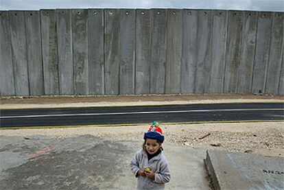 Un niño palestino, frente a la parte del muro de seguridad que Israel está levantando cerca de la aldea cisjordana de Masha.